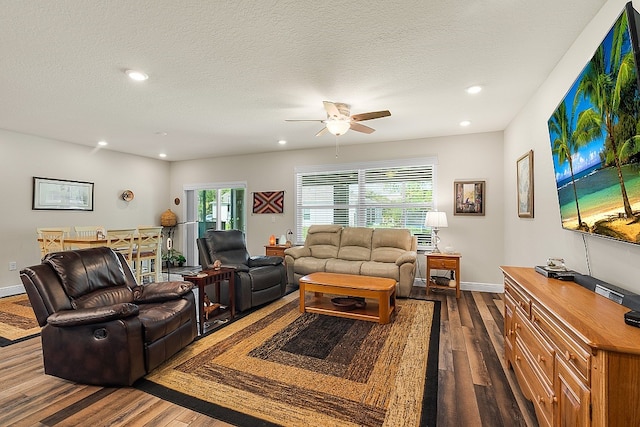 living room with ceiling fan, a textured ceiling, and dark hardwood / wood-style flooring