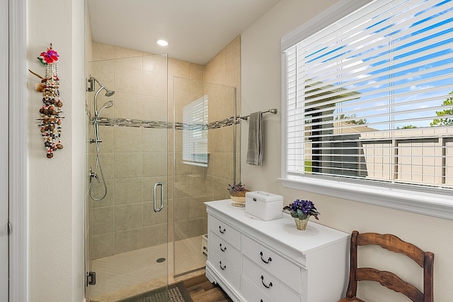 bathroom featuring a shower with shower door, vanity, and a healthy amount of sunlight