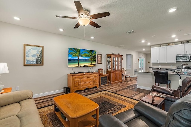 living room with hardwood / wood-style flooring, a textured ceiling, and ceiling fan