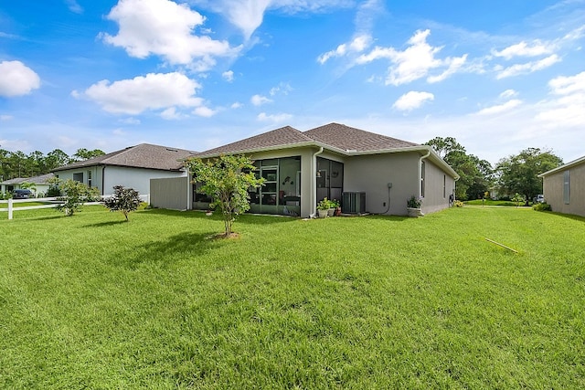 rear view of property with central AC and a yard