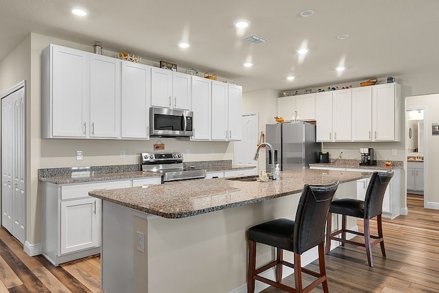 kitchen with white cabinets, an island with sink, and stainless steel appliances