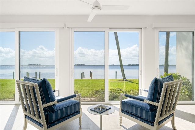 sunroom with ceiling fan and a water view