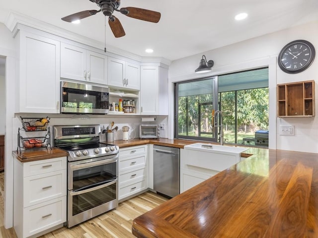 kitchen featuring ceiling fan, butcher block countertops, light hardwood / wood-style floors, white cabinetry, and stainless steel appliances