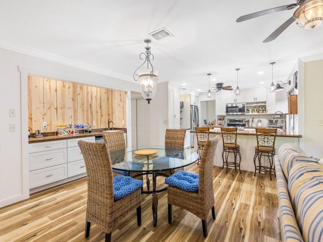 dining room featuring ornamental molding, sink, and light hardwood / wood-style flooring