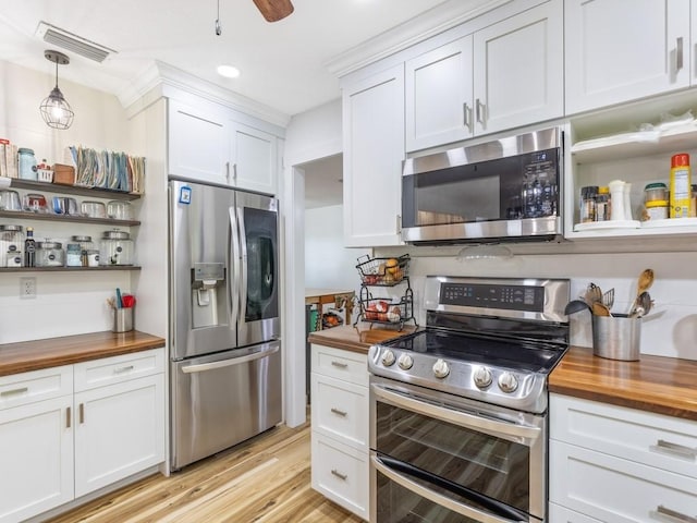 kitchen with white cabinetry, hanging light fixtures, butcher block countertops, appliances with stainless steel finishes, and light wood-type flooring