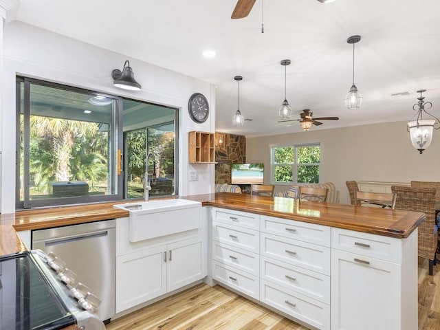 kitchen with white cabinets, kitchen peninsula, hanging light fixtures, and wooden counters