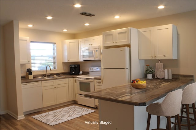 kitchen with white cabinetry, kitchen peninsula, white appliances, and sink