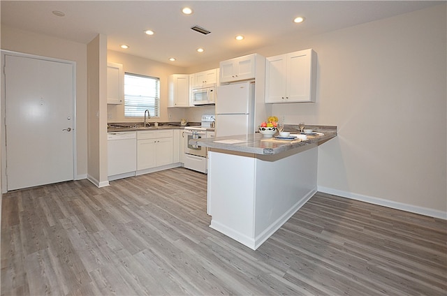 kitchen with white cabinetry, white appliances, sink, kitchen peninsula, and light hardwood / wood-style flooring