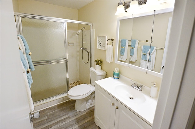 bathroom featuring hardwood / wood-style floors, a shower with shower door, vanity, and toilet