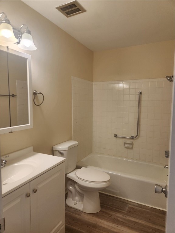 full bathroom featuring toilet, tiled shower / bath combo, vanity, and wood-type flooring