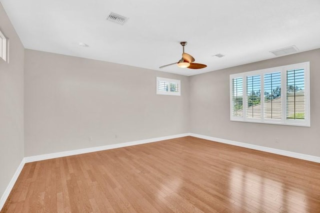 empty room with light wood-type flooring, visible vents, and baseboards