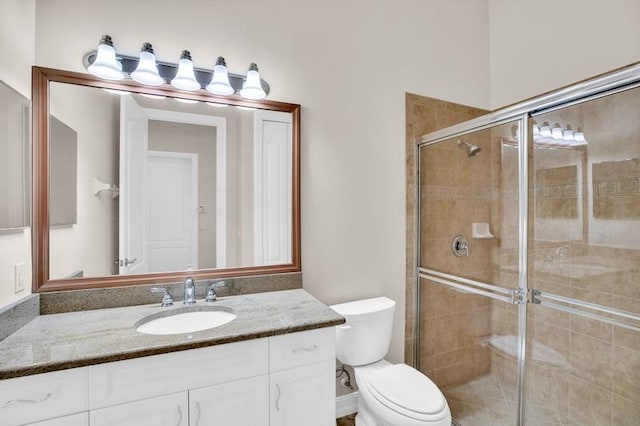 full bathroom with vanity, a shower stall, and toilet