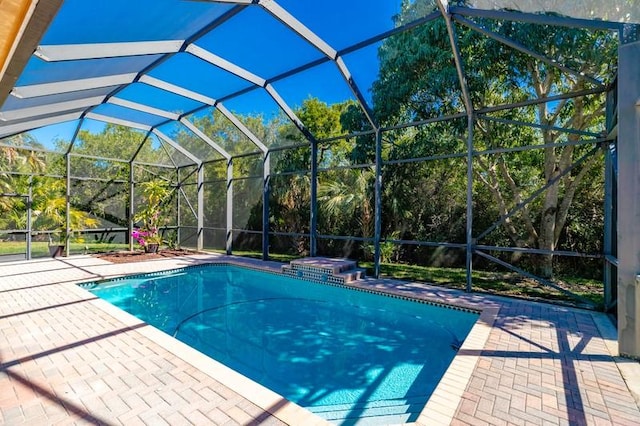 pool with glass enclosure, a hot tub, and a patio