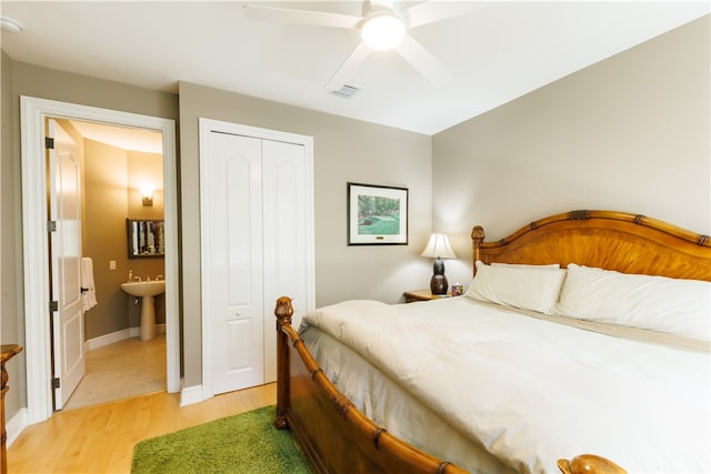 bedroom featuring sink, ensuite bathroom, ceiling fan, light hardwood / wood-style flooring, and a closet