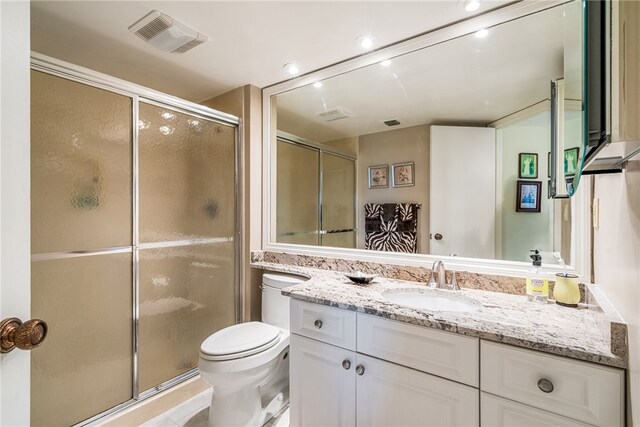 bathroom featuring toilet, vanity, and a shower with door