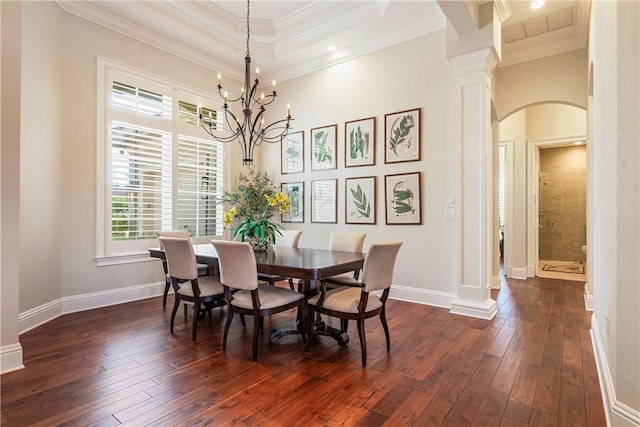 dining space featuring ornamental molding, dark hardwood / wood-style floors, a chandelier, and ornate columns