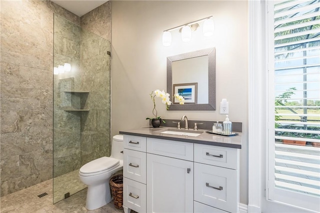 bathroom with vanity, toilet, and a tile shower