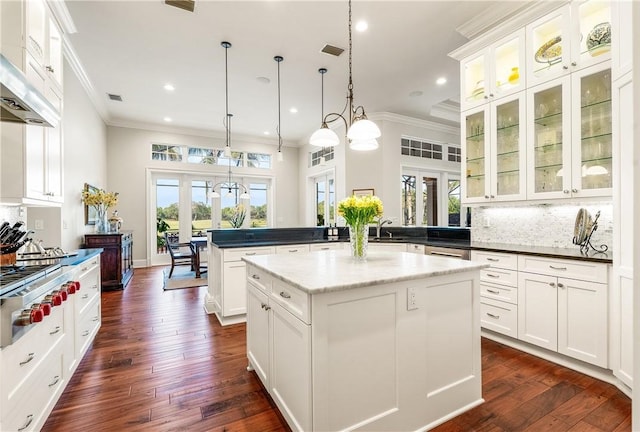 kitchen with hanging light fixtures, crown molding, a center island, and white cabinetry