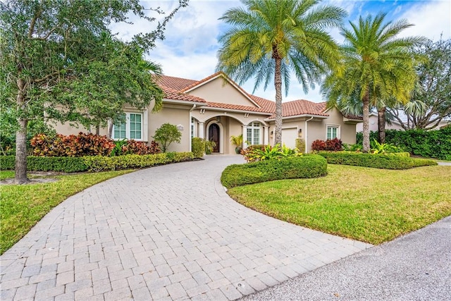 mediterranean / spanish-style home featuring a garage and a front lawn