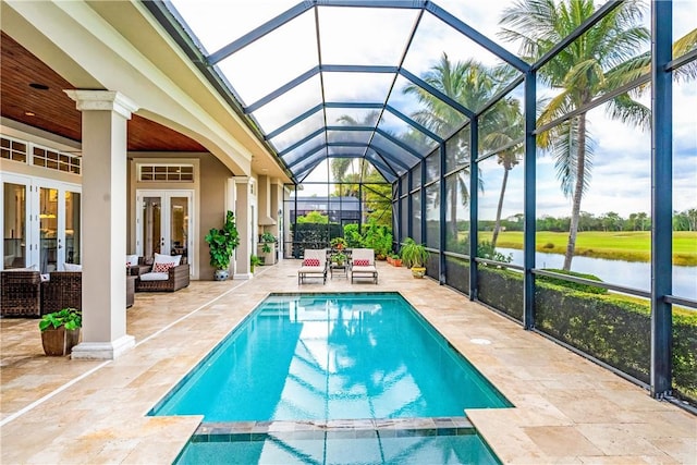 view of pool with a lanai, a water view, a patio area, and french doors