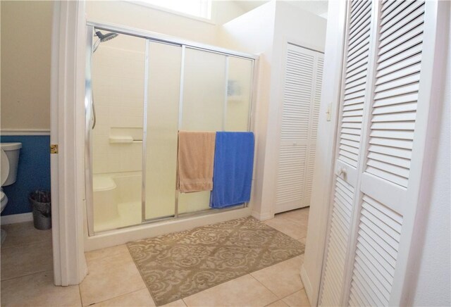 bathroom featuring tile patterned floors, toilet, and a shower with door