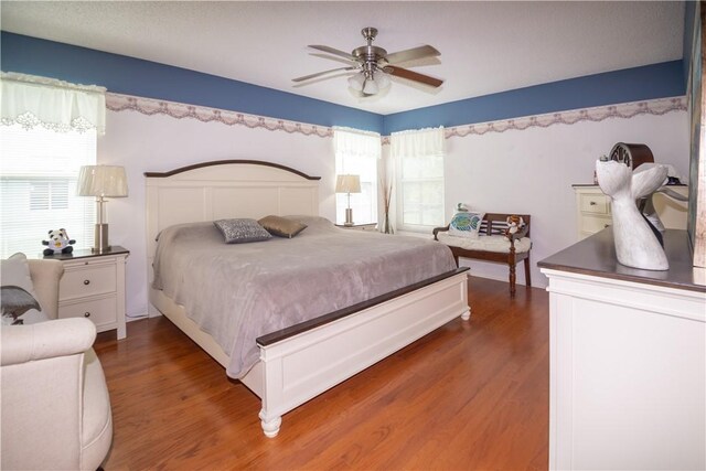 bedroom with multiple windows, dark hardwood / wood-style floors, and ceiling fan