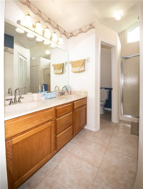 bathroom featuring tile patterned flooring, vanity, a shower with door, and toilet