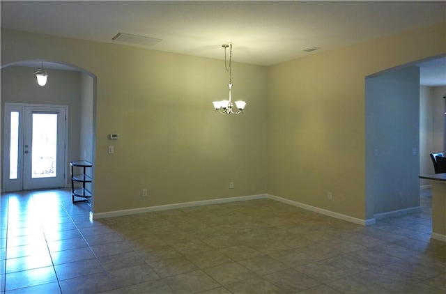 unfurnished room featuring arched walkways, a chandelier, visible vents, and baseboards