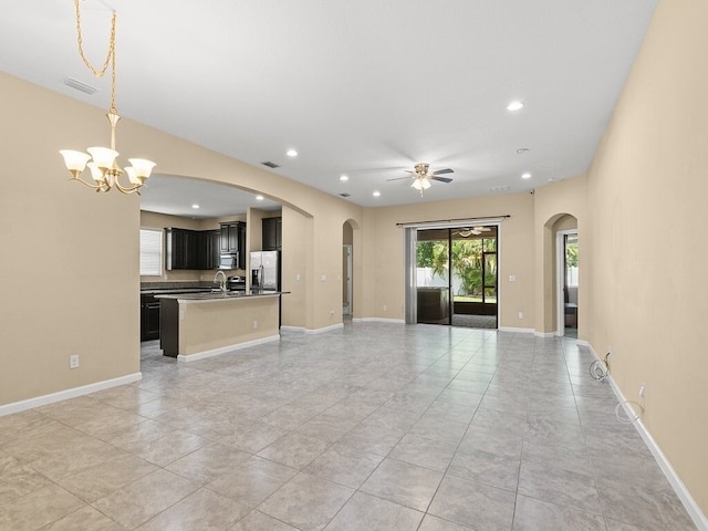 unfurnished living room featuring baseboards, ceiling fan with notable chandelier, visible vents, arched walkways, and recessed lighting