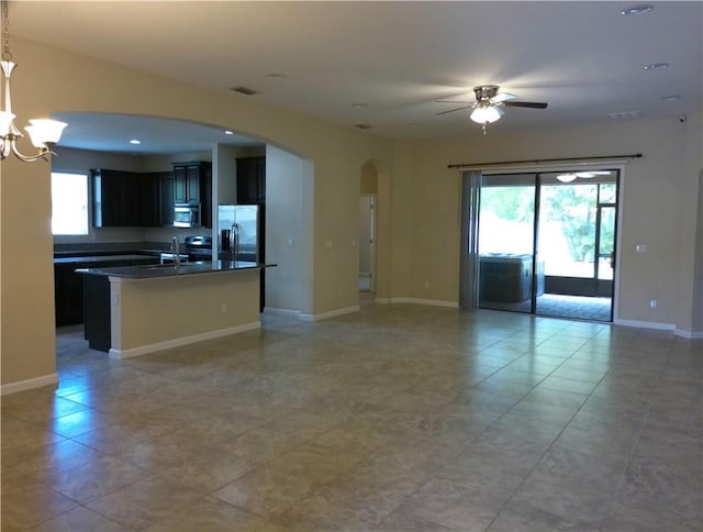 unfurnished living room featuring arched walkways, recessed lighting, visible vents, baseboards, and ceiling fan with notable chandelier