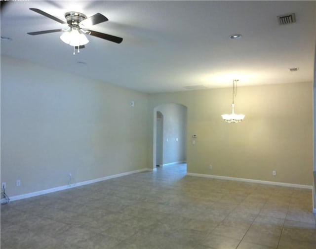 spare room with visible vents, arched walkways, baseboards, and ceiling fan with notable chandelier