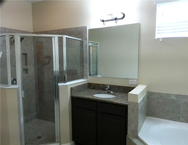 bathroom with a stall shower, a garden tub, and vanity