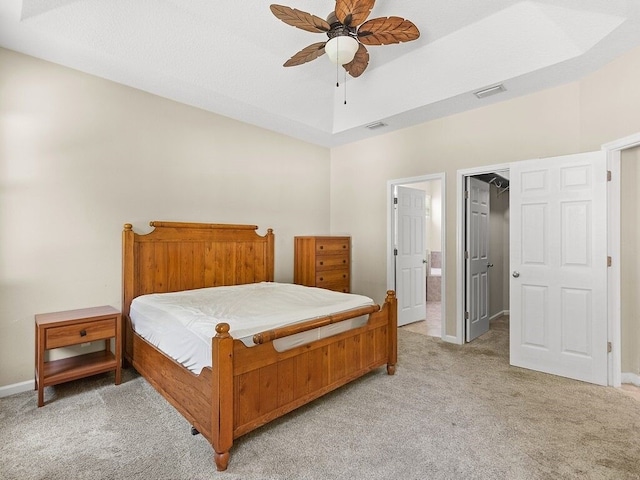 bedroom featuring connected bathroom, light carpet, a walk in closet, baseboards, and visible vents