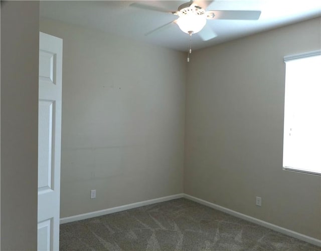 carpeted empty room with a healthy amount of sunlight, ceiling fan, and baseboards