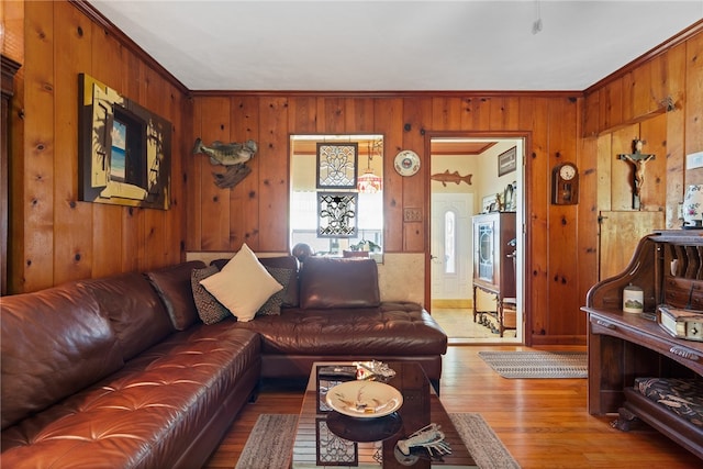 living room with hardwood / wood-style flooring, wooden walls, and crown molding