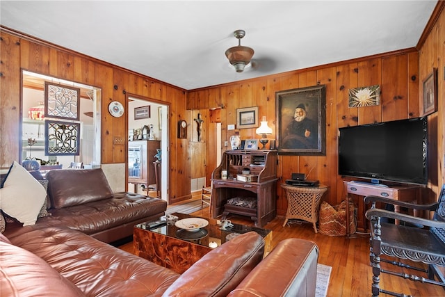 living room with wood-type flooring, wooden walls, and ornamental molding