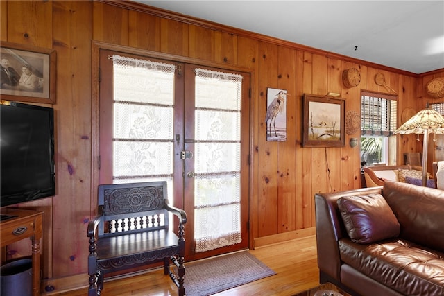 living room featuring wooden walls, french doors, ornamental molding, and wood-type flooring