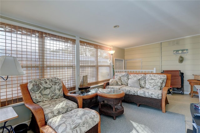 carpeted living room featuring wood walls and ornamental molding