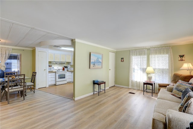 living room with light wood-type flooring, ornamental molding, and a wealth of natural light