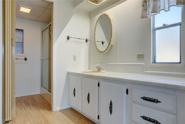 bathroom featuring a paneled ceiling, vanity, wood-type flooring, and a shower with door