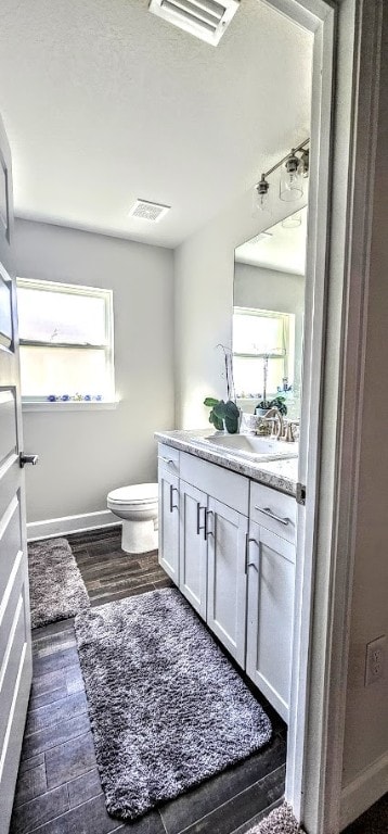 bathroom featuring wood-type flooring, vanity, and toilet