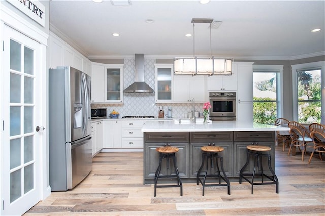 500 45th Ct SW, Vero Beach, FL 32968 - kitchen with appliances with stainless steel finishes, wall chimney range hood, ornamental molding, light countertops, and white cabinetry
