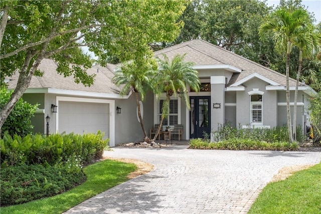 500 45th Ct SW, Vero Beach, FL 32968 - view of front of house with a garage, decorative driveway, stucco siding, roof with shingles, and a porch