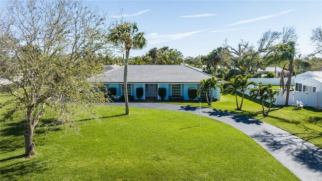 single story home with a front yard, a tile roof, driveway, and fence