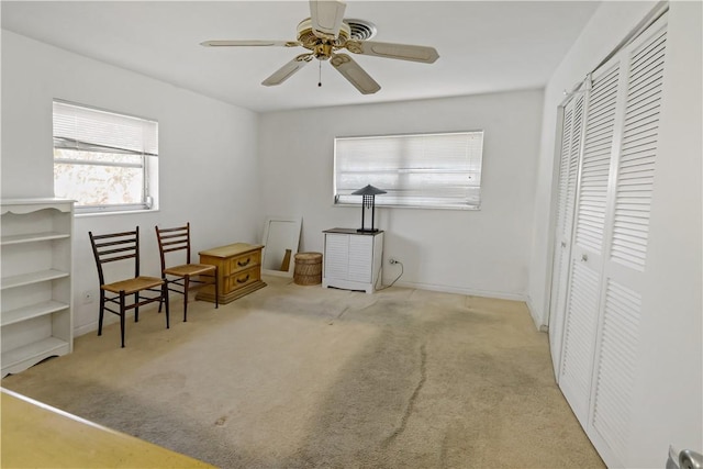 living area featuring light carpet and ceiling fan