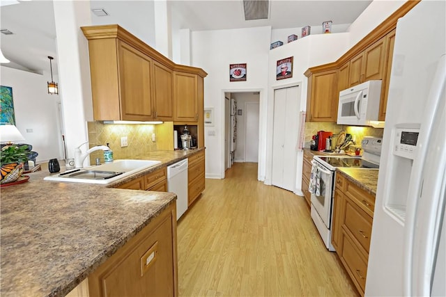 kitchen featuring decorative light fixtures, sink, light wood-type flooring, backsplash, and white appliances