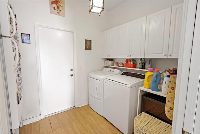 washroom featuring light hardwood / wood-style floors, washing machine and dryer, and cabinets