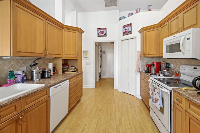 kitchen with sink, decorative backsplash, light hardwood / wood-style floors, light stone countertops, and white appliances