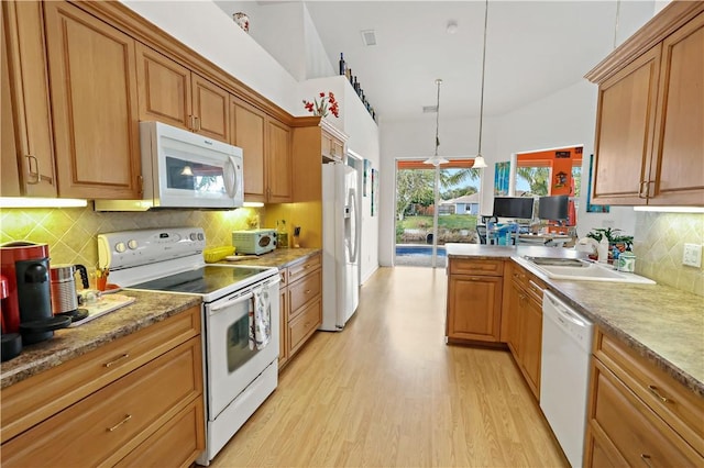 kitchen featuring sink, white appliances, light hardwood / wood-style floors, decorative light fixtures, and vaulted ceiling