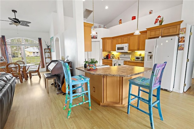 kitchen with a breakfast bar, hanging light fixtures, light hardwood / wood-style flooring, kitchen peninsula, and white appliances